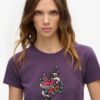 Camiseta ajustada con pequeño tatuaje de pedrería