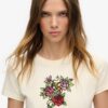 Camiseta ajustada con pequeño tatuaje de pedrería